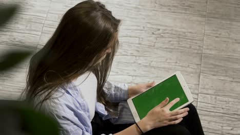 una chica bonita con una tableta sentada en el sillón
