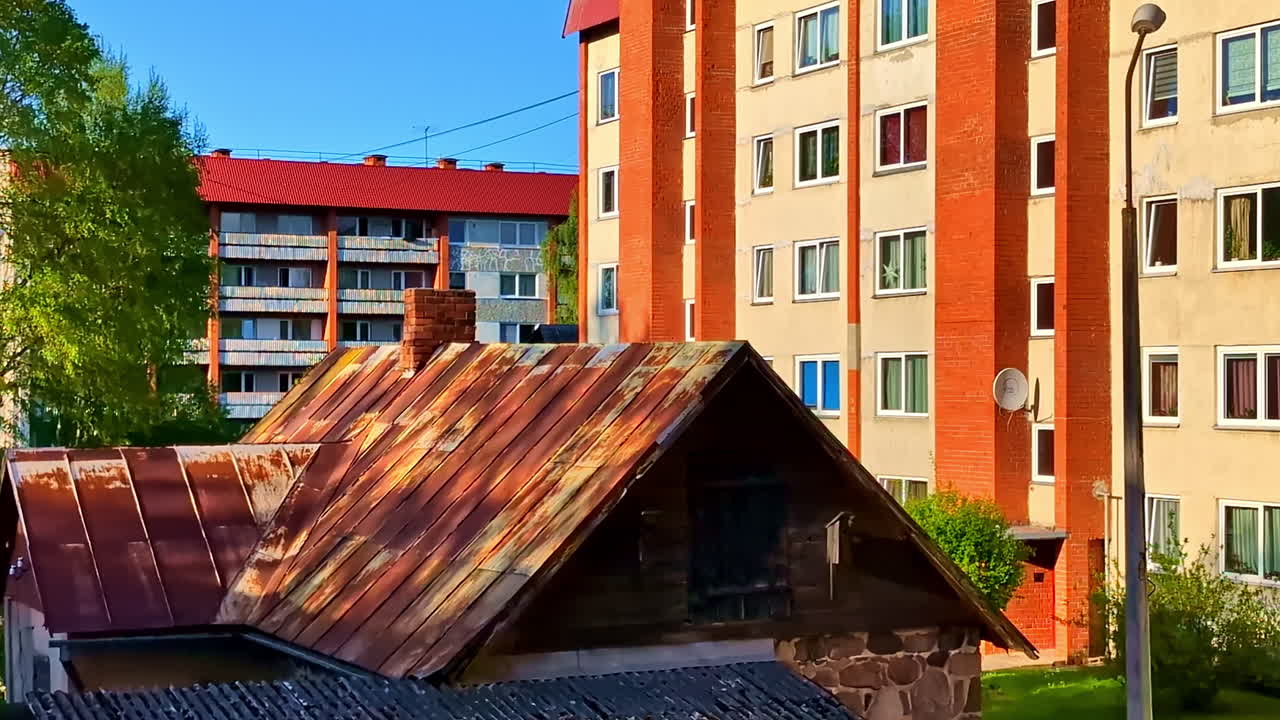 Rusty Roof of Stone Building in Front of Soviet Apartment Buildings at Sunrise
