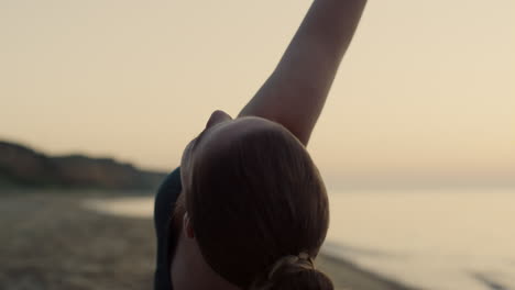 sportswoman practicing triangl asana on beach close up. woman training yoga.