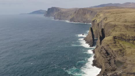 Vista-Aérea-De-La-Cascada-Bösdalafossur-Y-La-Pila-Marina-Geitaskorardrangur-En-Vagar,-Islas-Feroe