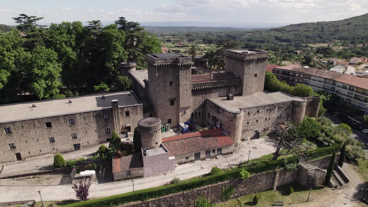 Aerial view orbiting Jarandilla castle medieval stone wall with round towers and battlements, C&aacute;ceres