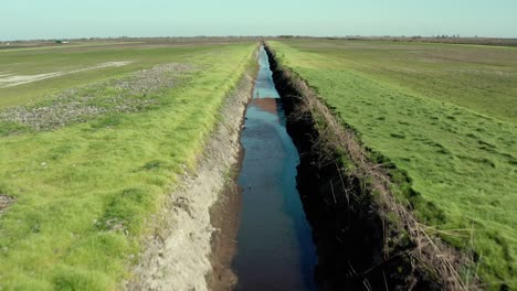 Aerial:-trench-in-a-field-in-Stockton,-California,-flying-forward-drone