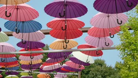 decoración de callejón hecha de filas de paraguas de colores vivos colgando por encima contra el cielo azul en la isla de hierbas en pocheon - pan