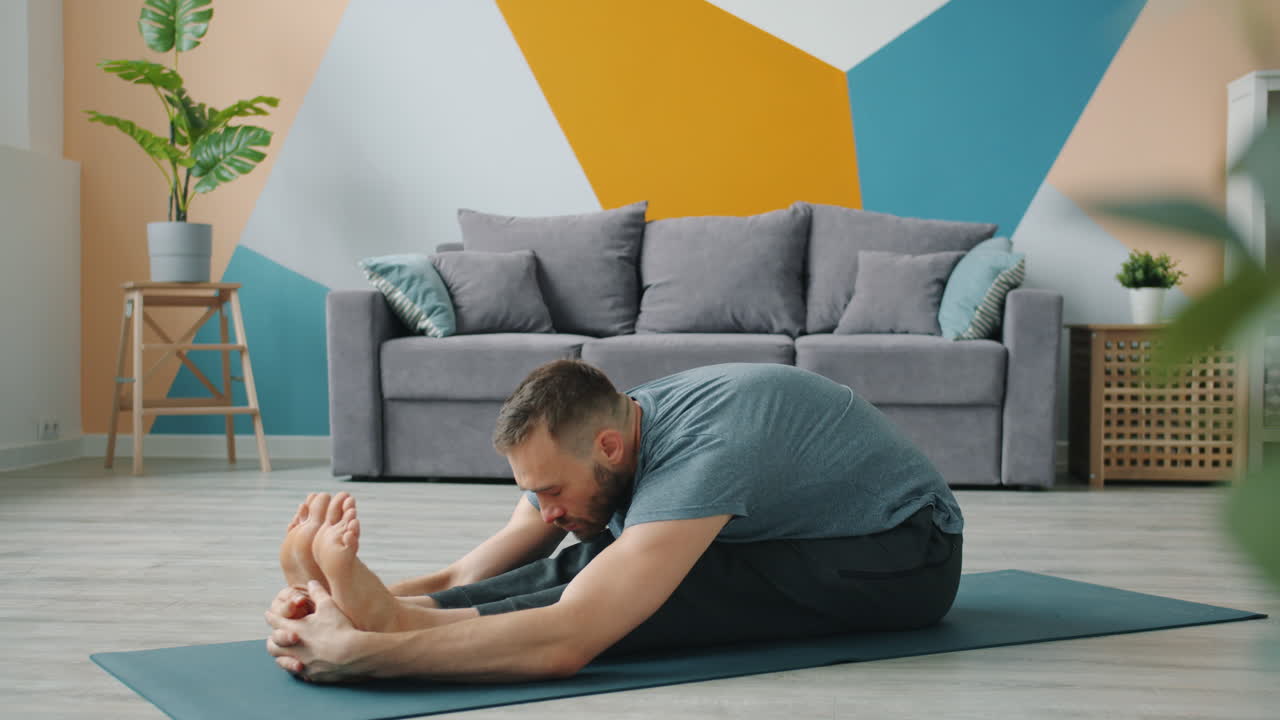 Man Doing Seated Forward Bend Yoga Pose at Home