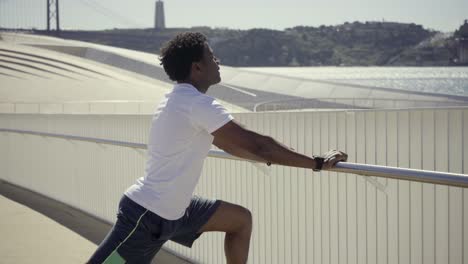 concentrated african american man warming up near metal railing.