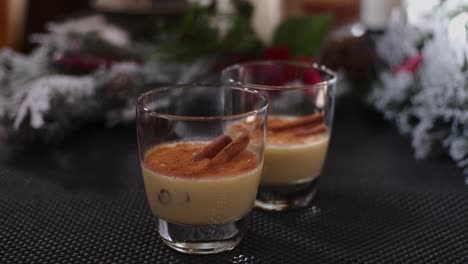 A-slow-push-in-into-two-glasses-of-holiday-drink-Christmas-eggnog-garnished-with-cinnamon-sticks