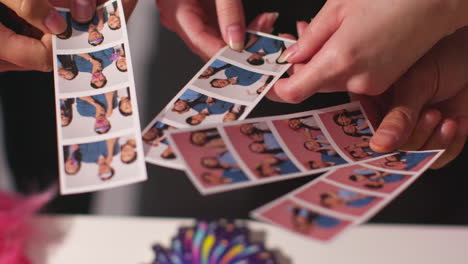 close up of a group of friends having fun looking at prints from photo booth with props 7