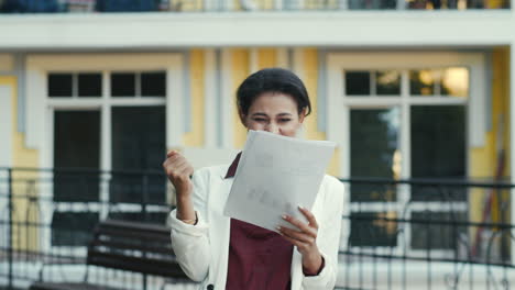 feliz mujer de negocios de raza mixta leyendo documentos en la calle urbana. dama al aire libre