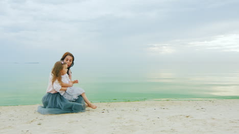 Young-Mother-With-A-Girl-Three-Years-Sitting-On-The-Beach-Chatting