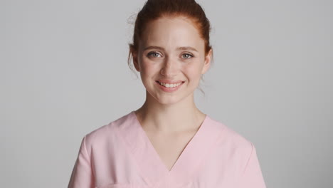 Redheaded-nurse-in-front-of-camera-on-gray-background.