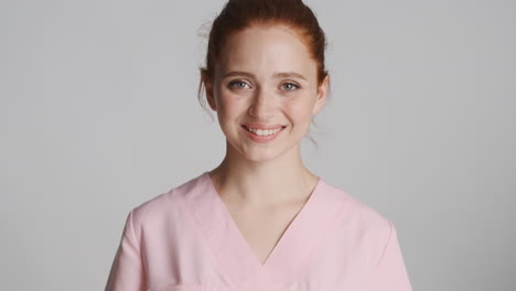 redheaded nurse in front of camera on gray background.