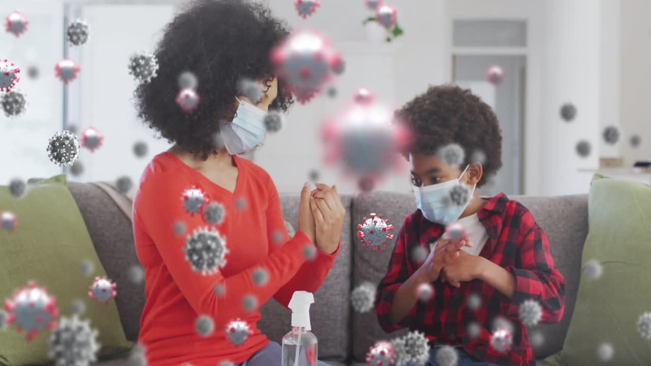 Animation of virus cells over african american mother with son disinfecting hands