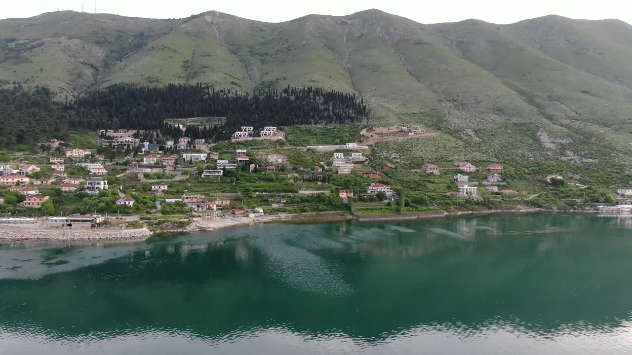 Drone view in Albania flying over Shkod&euml;r lake in Pogradec on cloudy day with green mountains on the back horizontal move