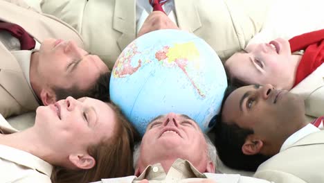 business team on floor in a circle with a terrestrial globe in the center