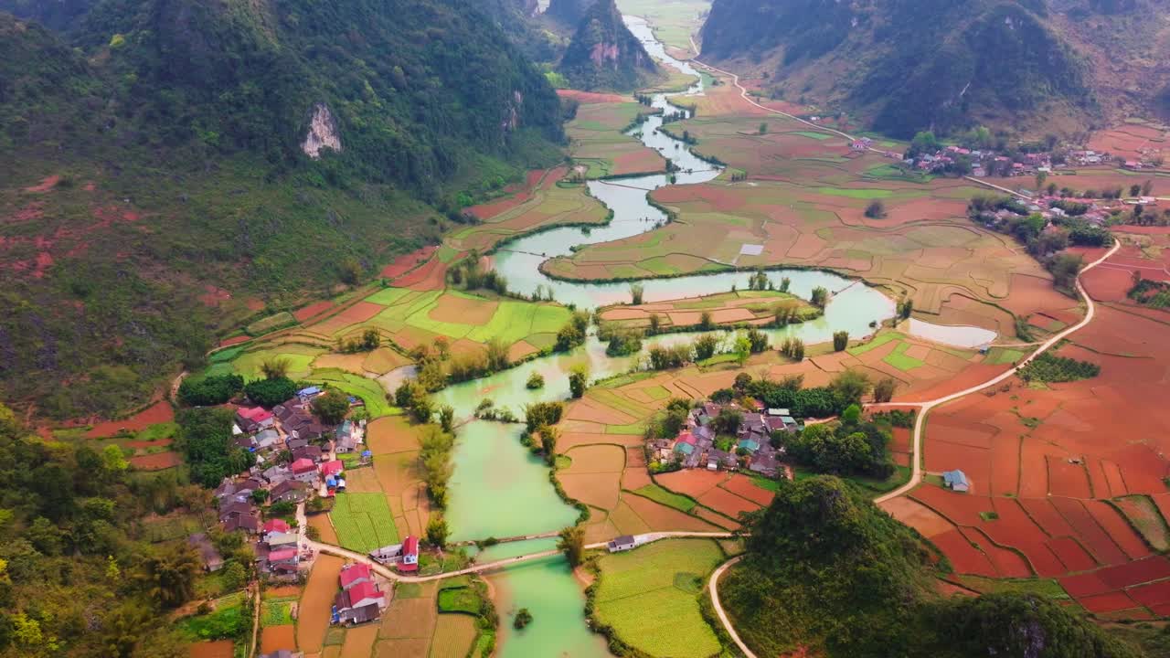 This drone footage captures the breathtaking beauty of Phong Nam Valley in Cao Bang. The video showcases a majestic winding river flowing through lush green rice fields, framed by rugged mountains.