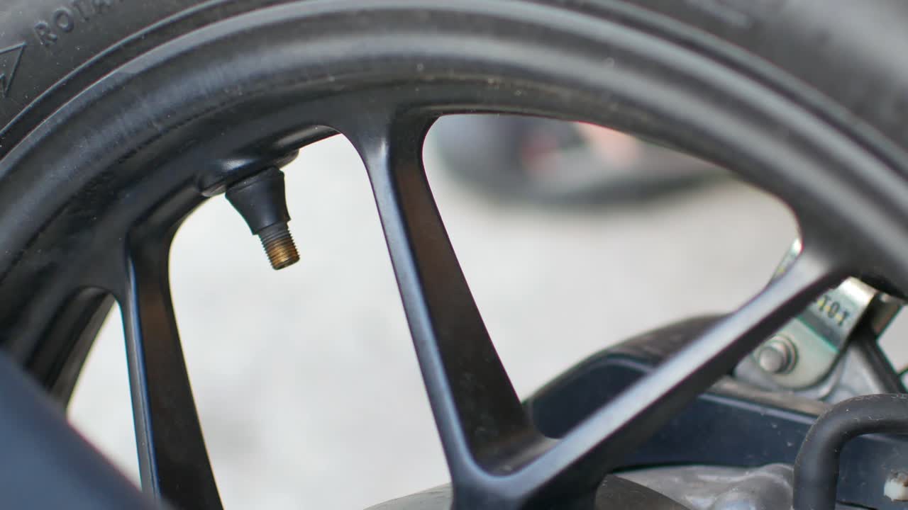 POV to the man's hand while inflate the tier-wheel of motorcycle-motorbike in daytime. inflate, pump into wheel-tier.