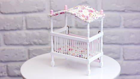 tiny baby crib rotating on the table. curved little bed with colorful mattress and top close up.