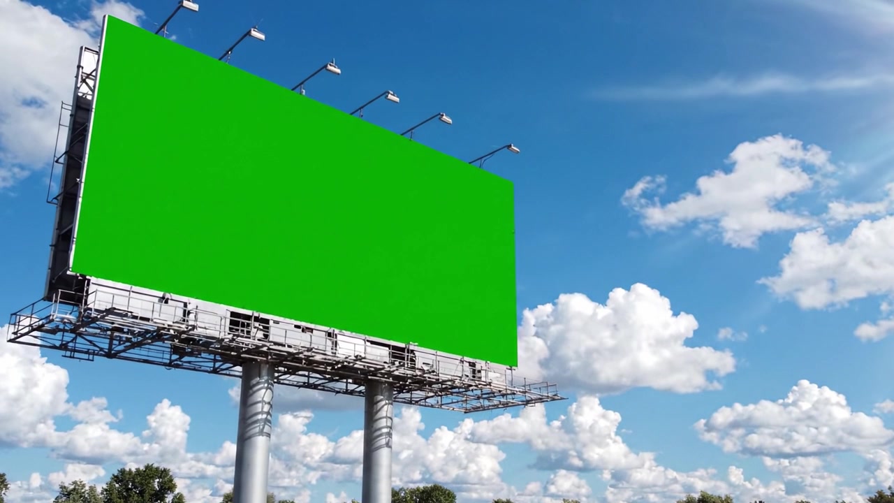 Et tomt grønt reklameskilt står højt mod en klar blå himmel med bløde hvide skyer, og tilbyder en perfekt plads til kreative reklame- og marketingkampagner.