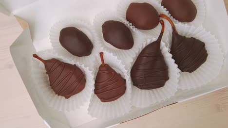 dried pears and dates in chocolate. chocolate candies in crafting gift box extreme close-up rotating. assorted chocolates confectionery on the white background