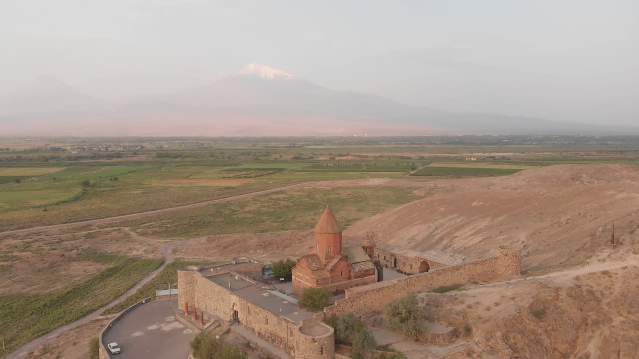 vista aérea en movimiento lento del círculo alrededor del punto de referencia histórico en armenia - el monasterio de khor virap con el fondo del pico de la montaña ararat al amanecer