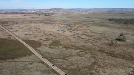 Una-Carretera-Con-Automóviles-Atraviesa-Un-Campo-Cubierto-De-Estanques-Primaverales-Protegidos-En-El-Valle-Central-De-California-Visto-En-Un-Episodio-De-California&#39;s-Gold