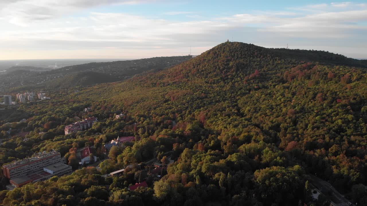 Slow aerial orbit view of Budapest from above Buda forest, golden hour