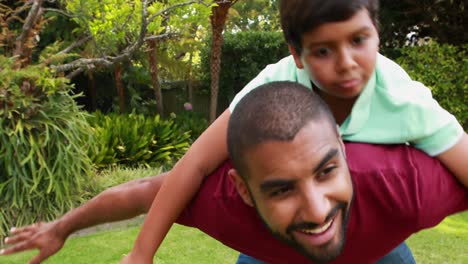 Father-giving-son-piggyback-ride-in-garden-4k