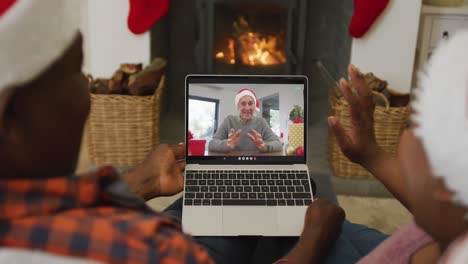 Afroamerikanisches-Paar-Mit-Weihnachtsmützen-Nutzt-Laptop-Für-Weihnachtsvideoanruf-Mit-Mann-Auf-Dem-Bildschirm