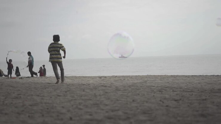 Una bolla che vola davanti alla macchina fotografica mentre persone giocano sulla spiaggia