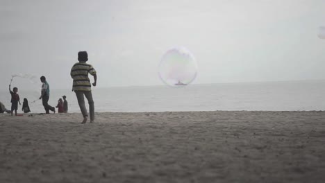 一個泡泡在攝影機前飛翔,而人們在海灘上玩耍