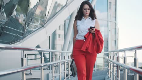 mujer de negocios confiada en un traje formal camina contra el fondo de un centro de negocios moderno
