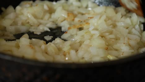 frying onions in a pan with oil. stir onion in skillet with wooden spatula