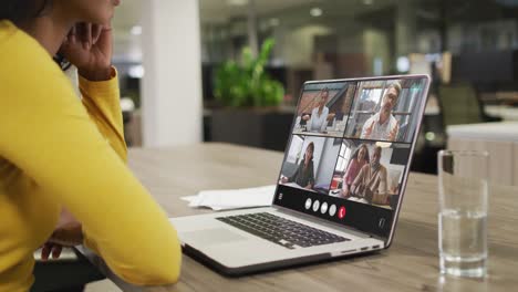 Mujer-Birracial-Usando-Una-Computadora-Portátil-Para-Videollamadas,-Con-Diversos-Colegas-De-Negocios-En-La-Pantalla