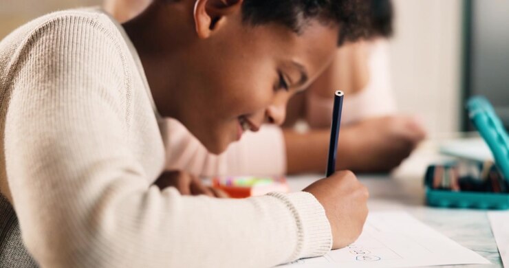 Young Boy Writing on Paper with Pencil at Home
