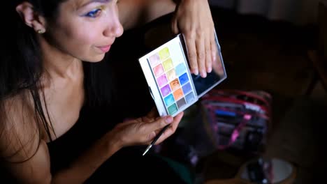 female video blogger applying eyeshdow in front of mirror 4k