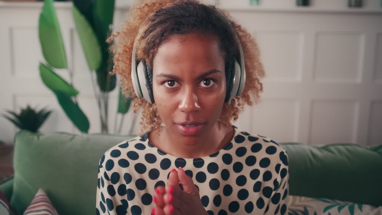 Smiling young woman in headphones having web call or virtual meeting