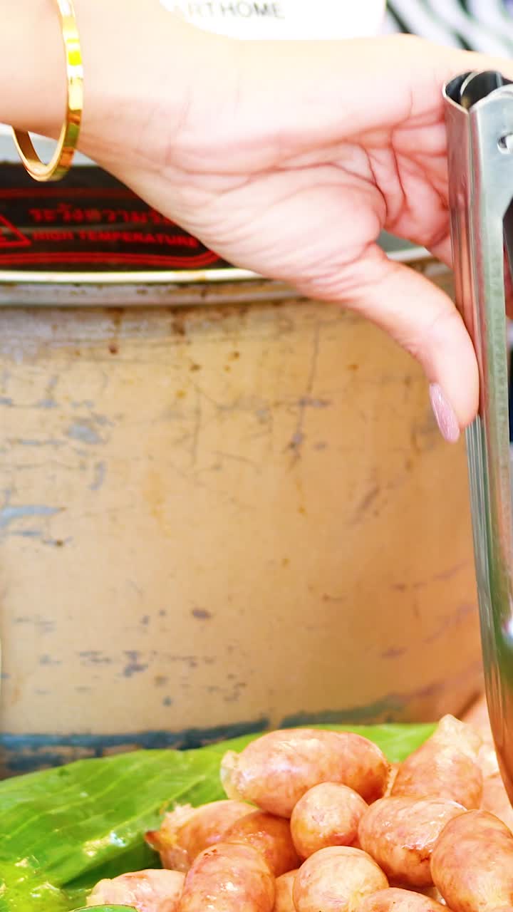 Vendor preparing sausages with scissors and tongs