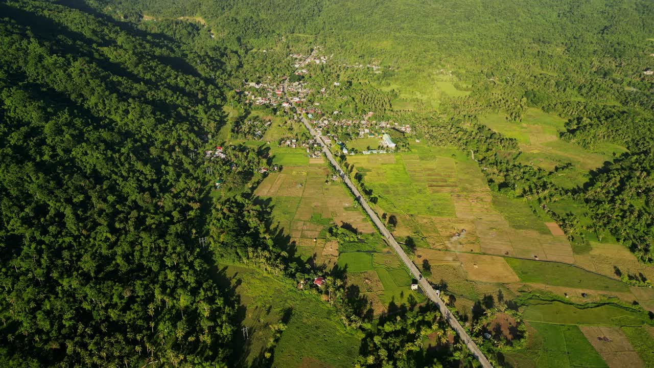 Aerial view of rural highway road along lush, tropical countryside setting during daytime at San Andres, Catanduanes, Bicol, Philippines.