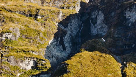 Toma-De-Arriba-Hacia-Abajo-De-Rocas-Morrenas-Con-Vegetación-De-Montañas-Iluminadas-Por-El-Sol---Valle-De-Rees,-Nueva-Zelanda