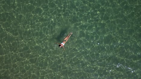 a young woman floats and enjoys the waters of the aegean sea near paros island in greece