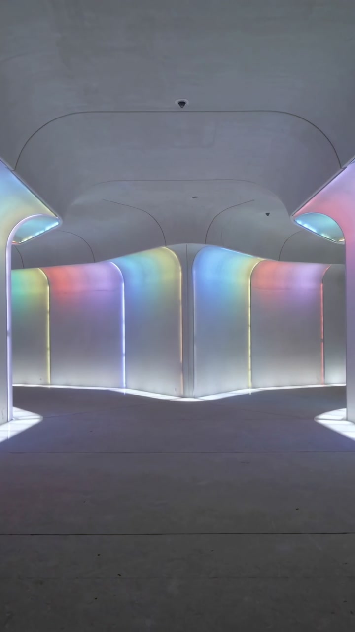 Vertical video: Smart lights cycling across curved panels in design gallery, dome camera monitoring