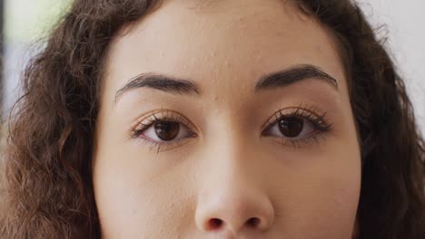 close up video portrait of opening eyes of biracial woman smiling to camera indoors