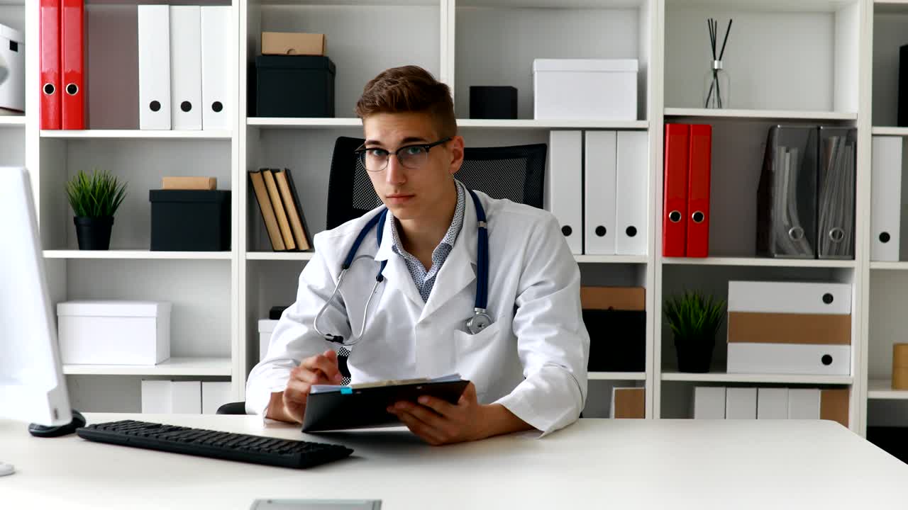 Young doctor working with documents at computer