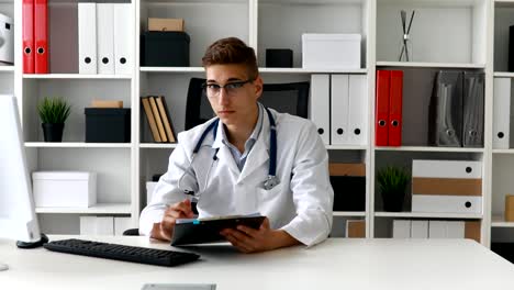 joven médico trabajando con documentos en la computadora