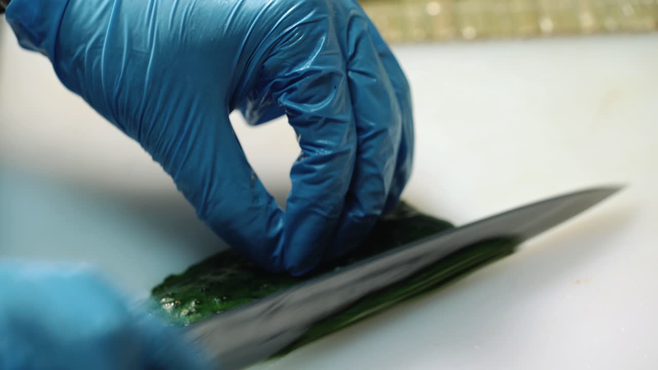 Hands of man prepare sushi. Slices of cucumber on rice. Every layer gives new taste. Sushi chef's difficult task.