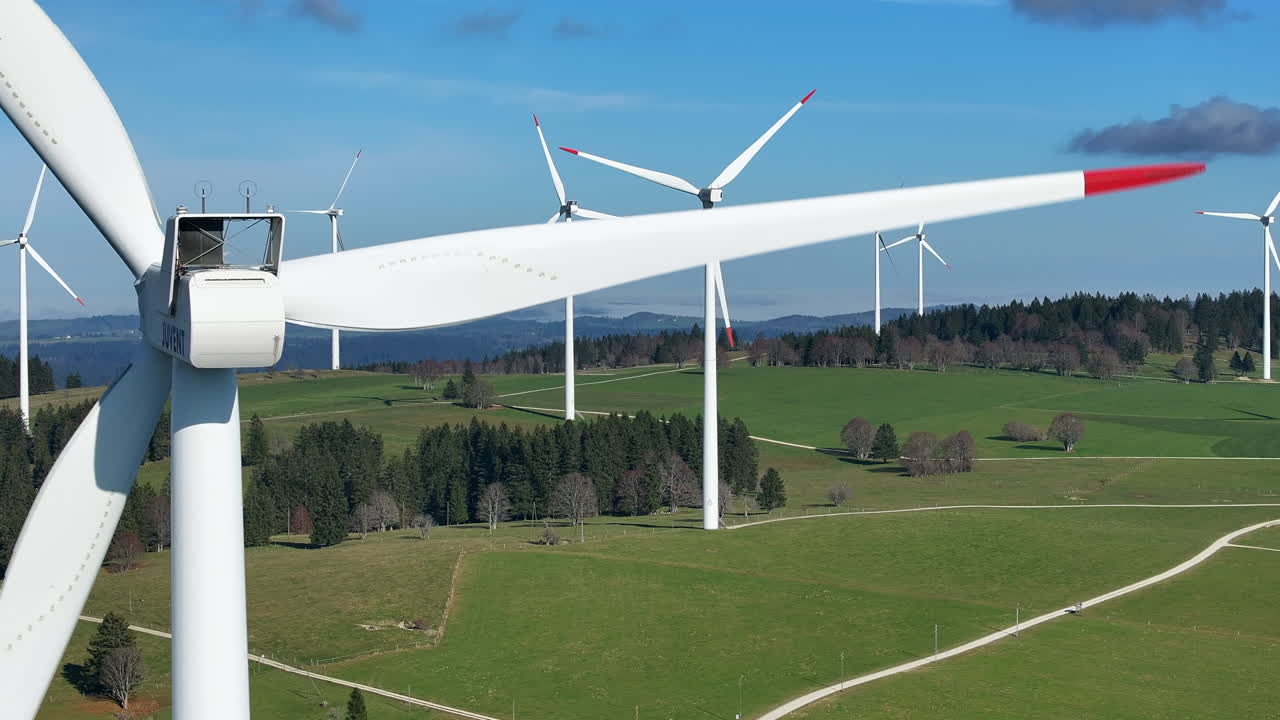 ветряные турбины вращаются на зеленом склоне холма под чистым голубым небом, запечатлены в крупном плане.