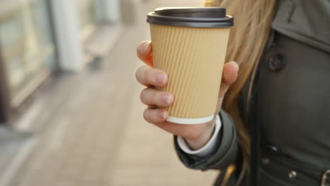 mujer rubia sostiene una taza de café ecológica y bebe una bebida