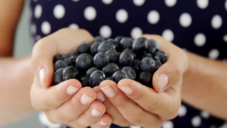 close-up of woman holding blueberry