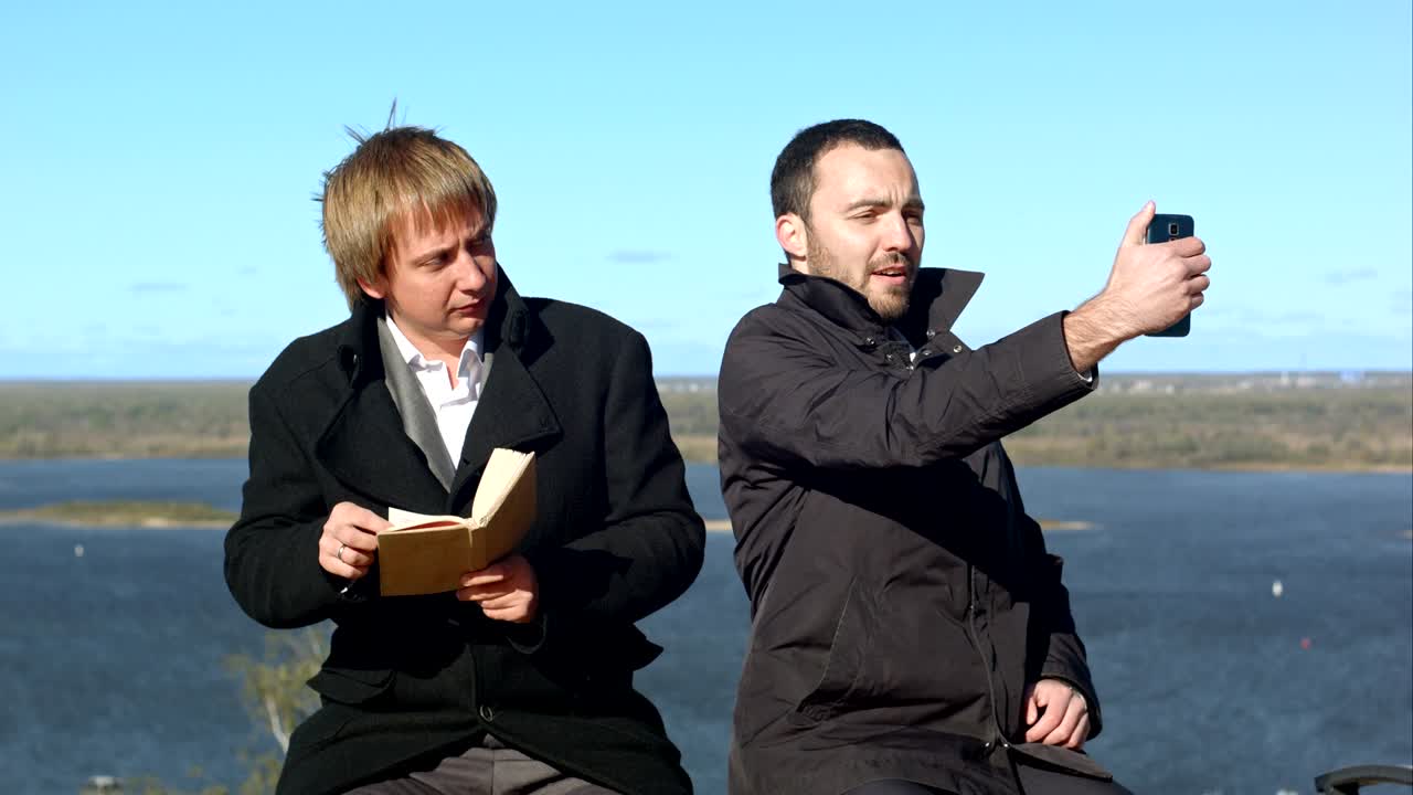 бизнесмен, поднимающий палец и делающий селфи на скамейке на открытом воздухе