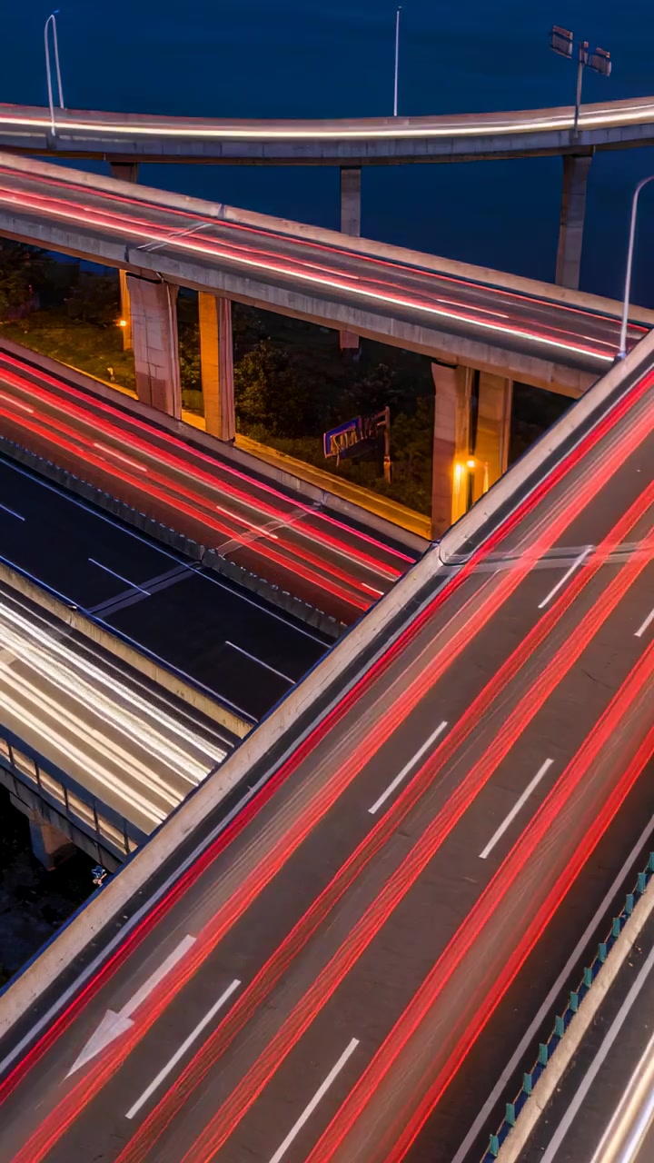Video verticale: Scie luminose fluide generate da auto in movimento su rampe a più livelli di notte.